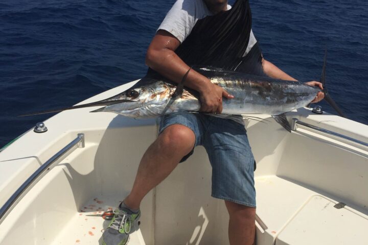 Member with a fresh catch on the bow of a club center console