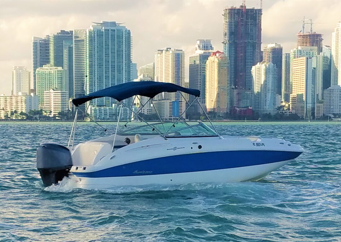 Hurricane deck boat from the club fleet running Biscayne Bay with the Brickell skyline behind