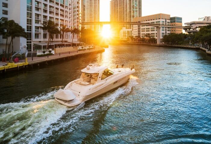 Boat cruising the Miami River at golden hour with the city skyline behind