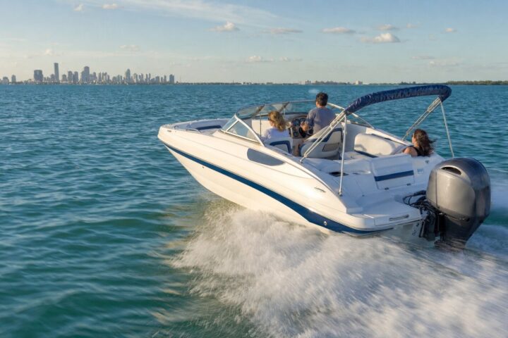 Hurricane SunDeck 2200 deck boat underway on Biscayne Bay with the Miami skyline behind